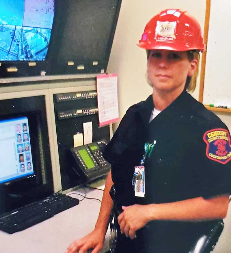 Female security officer stands watch at CCTV monitors.