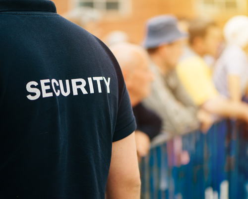 CrowdStrike_PublicSafety Close up of security guard's shirt at an outdoor event with a crowd.