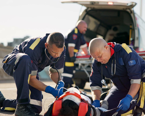 EmergencyMgmt_PublicSafety Three men assist an injured person at an emergency scene.