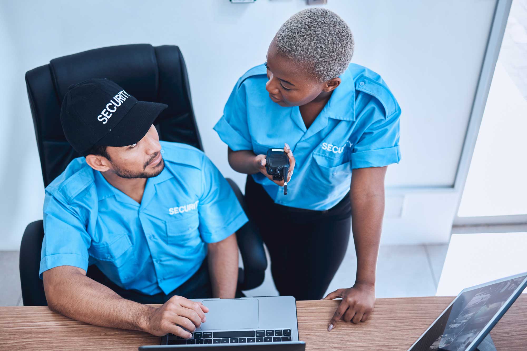 Two security officers talk at computer.